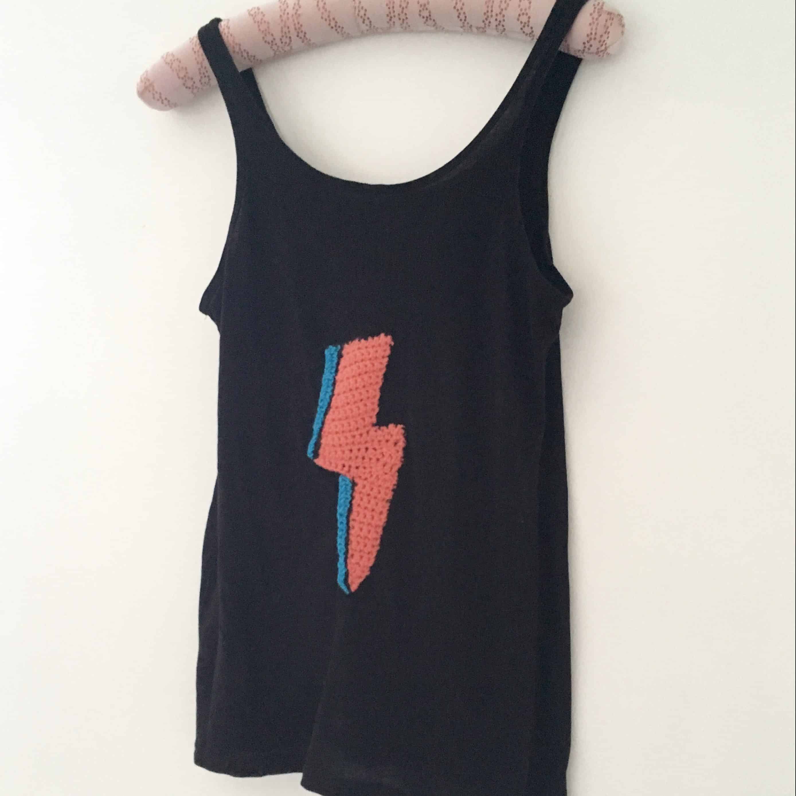 black vest with Bowie colours crochet lightning bolt embellished hanging on white wall