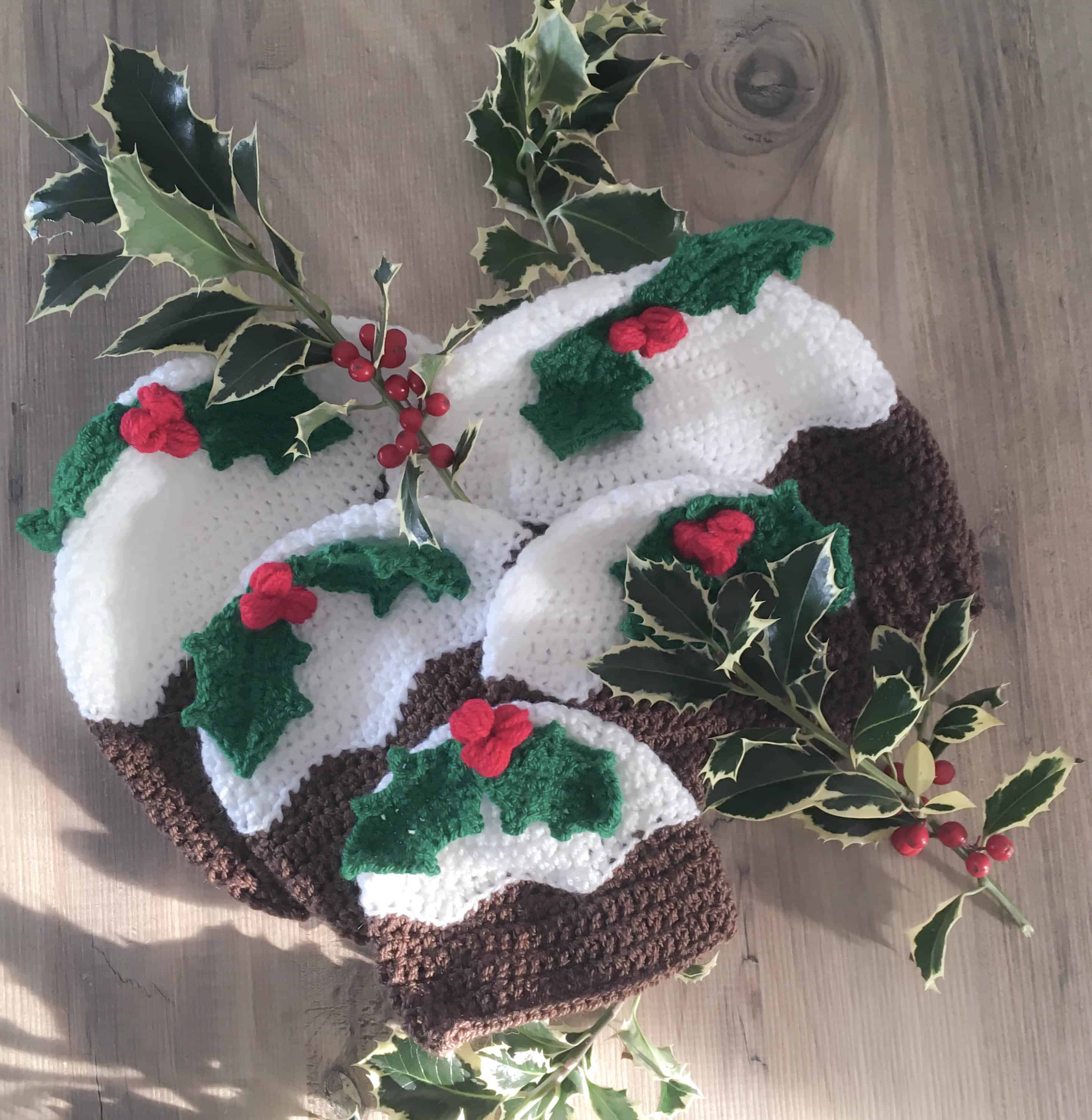 multiple sizes of crochet christmas pudding hats with holly leaf and berries
