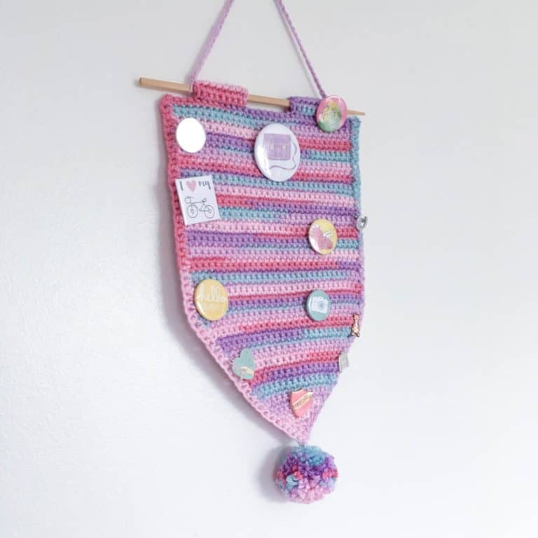 crochet pennant banner with pom-pom displaying enamel pins and badges