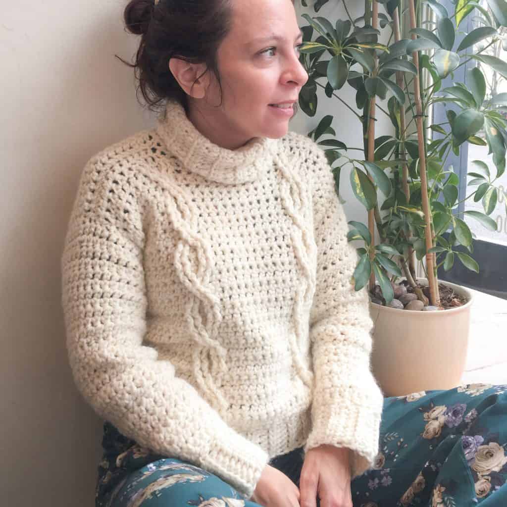 Girl looking out window wearing cabled crochet sweater