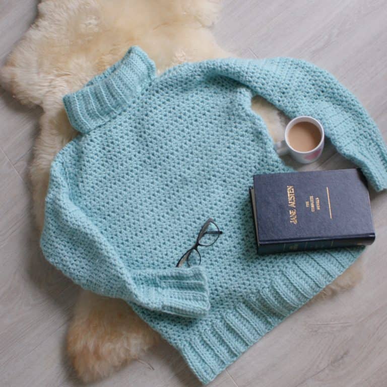 Cosy Crochet Sweater with cuppa book glasses on sheep pelt