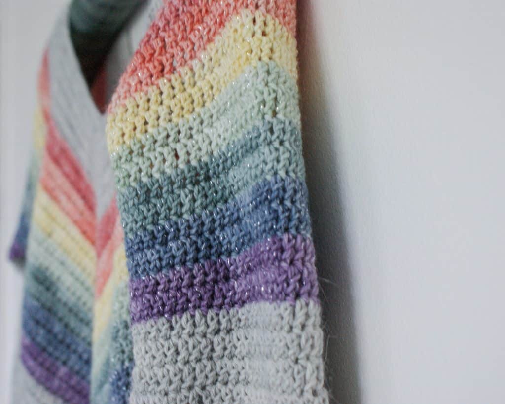 Close up of Crochet Rainbow Sweater hanging on white wall