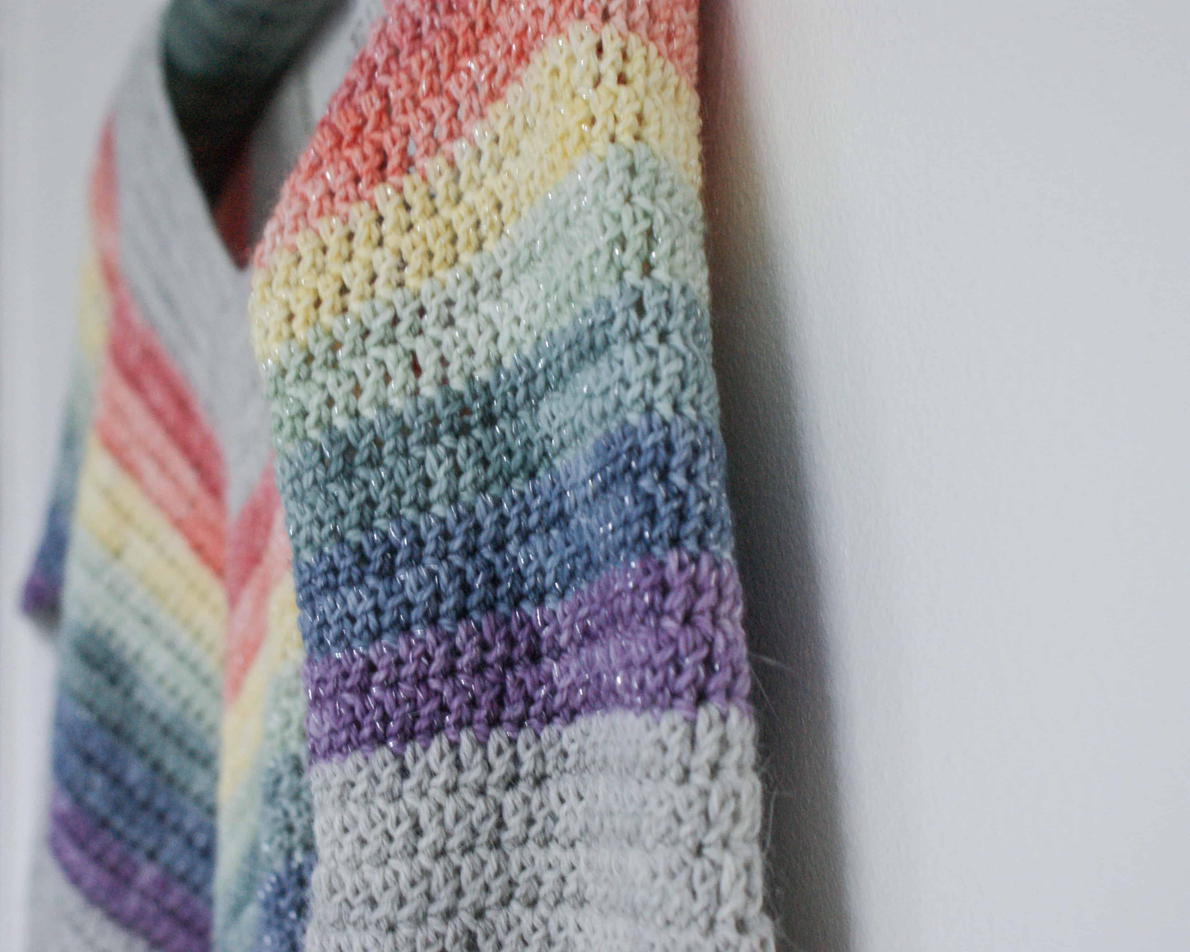 Close up of Crochet Rainbow Sweater hanging on white wall