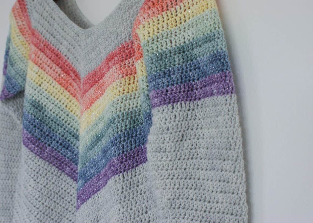 Close up of Crochet Rainbow Sweater hanging on white wall