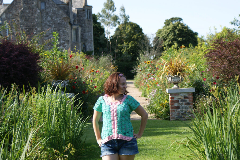 Dora wears the crochet summer solstice t-shirt whilst walking through some formal gardens.