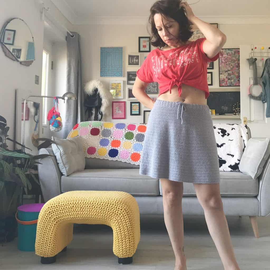 Woman standing in living room wearing crochet skirt and a red vest