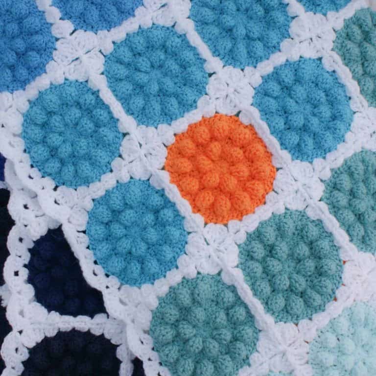 Bobble pop crochet blanket made from blue and orange bobbly circles on white boarder