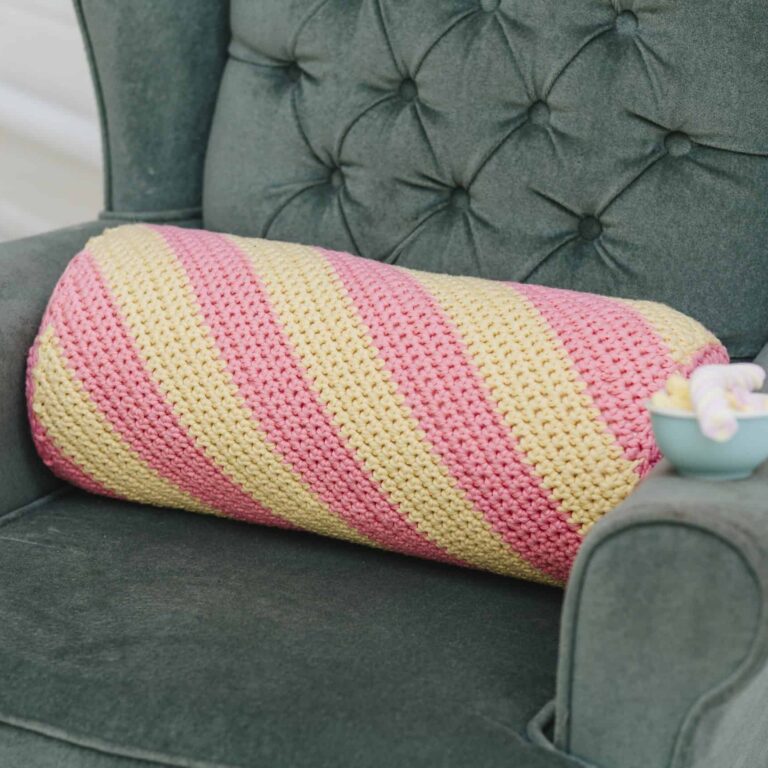 close up of pink and yellow flump pillow on green velvet chair