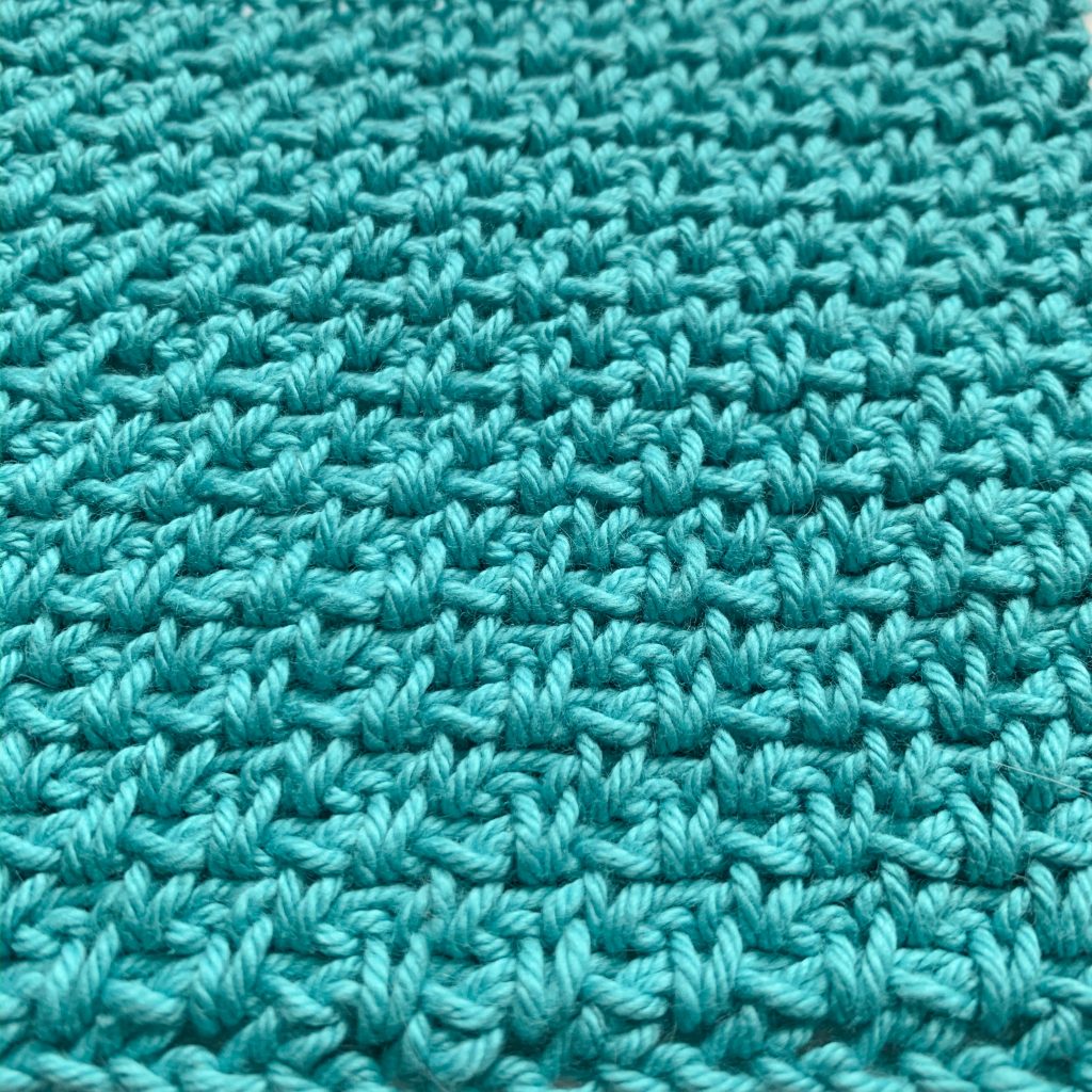 Close up of a moss stitch crochet swatch in turquoise
