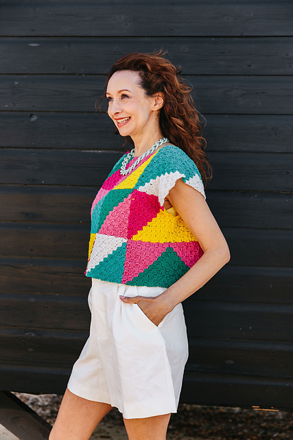 A woman in a colourful sleeveless crochet top made with the corner to corner stitch.