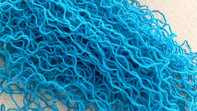 a pile of turquoise frogged yarn that looks tangled