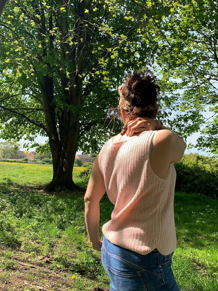 An image of the summer side crochet vest with sunlight felling on it through the trees.