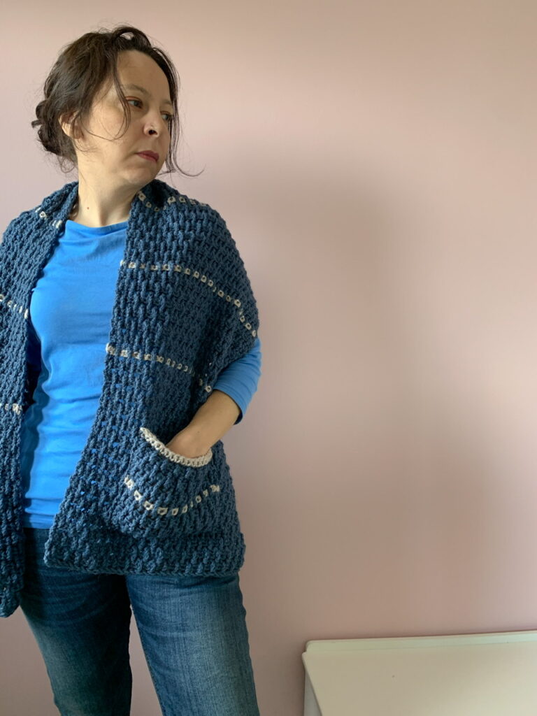 An uncrossed image of the bumps shawl, showing the corner of a white bench in the bottom of the image.