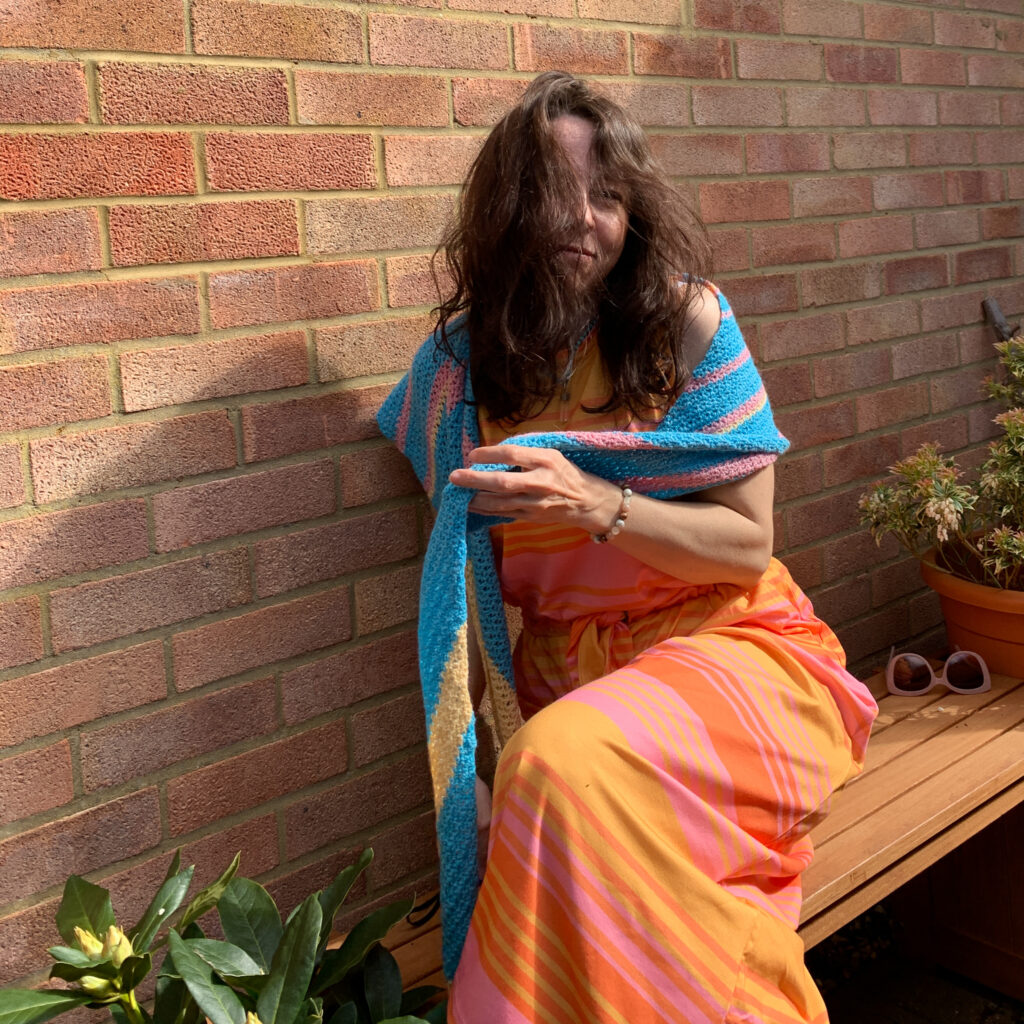 Dora laughs through her messy hair as she tries to throw a crochet shawl around her shoulders.