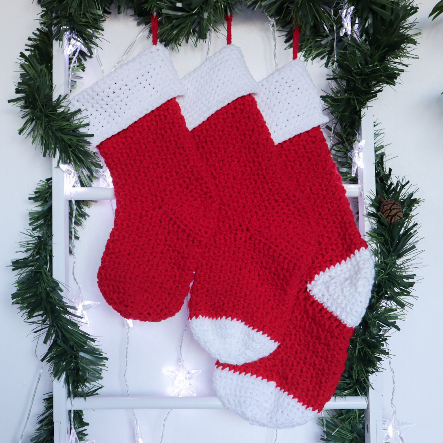 3 crochet stockings made in red and white yarn, hang in ascending order from small to large.