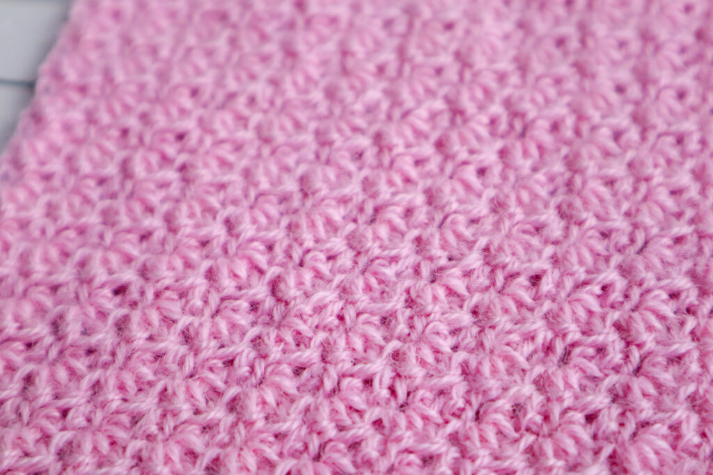 A close up of the paired extended single crochet stitch made in pink alpaca yarn.