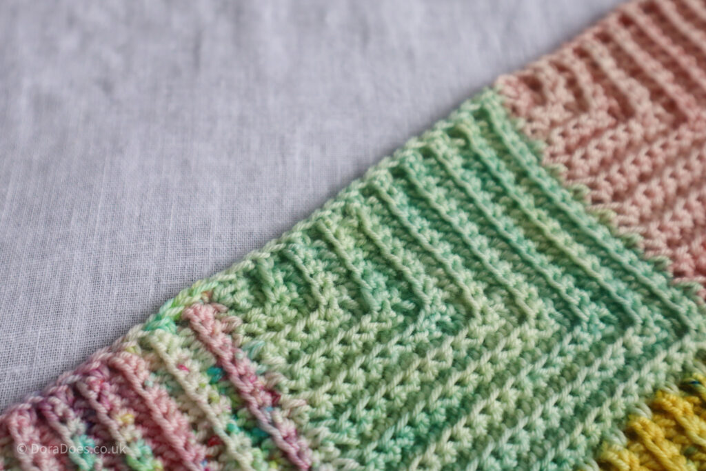 A close up of the edge of the mitered minis crochet scarf showing how to crochet a border as you work.