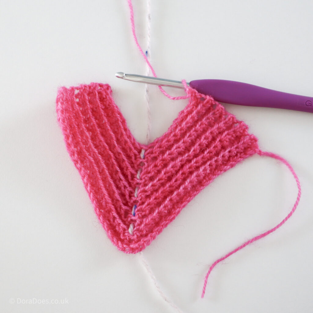 Crochet mitred square tutorial using pink yarn and a 4mm crochet hook, square shown over half way through: Step 11.