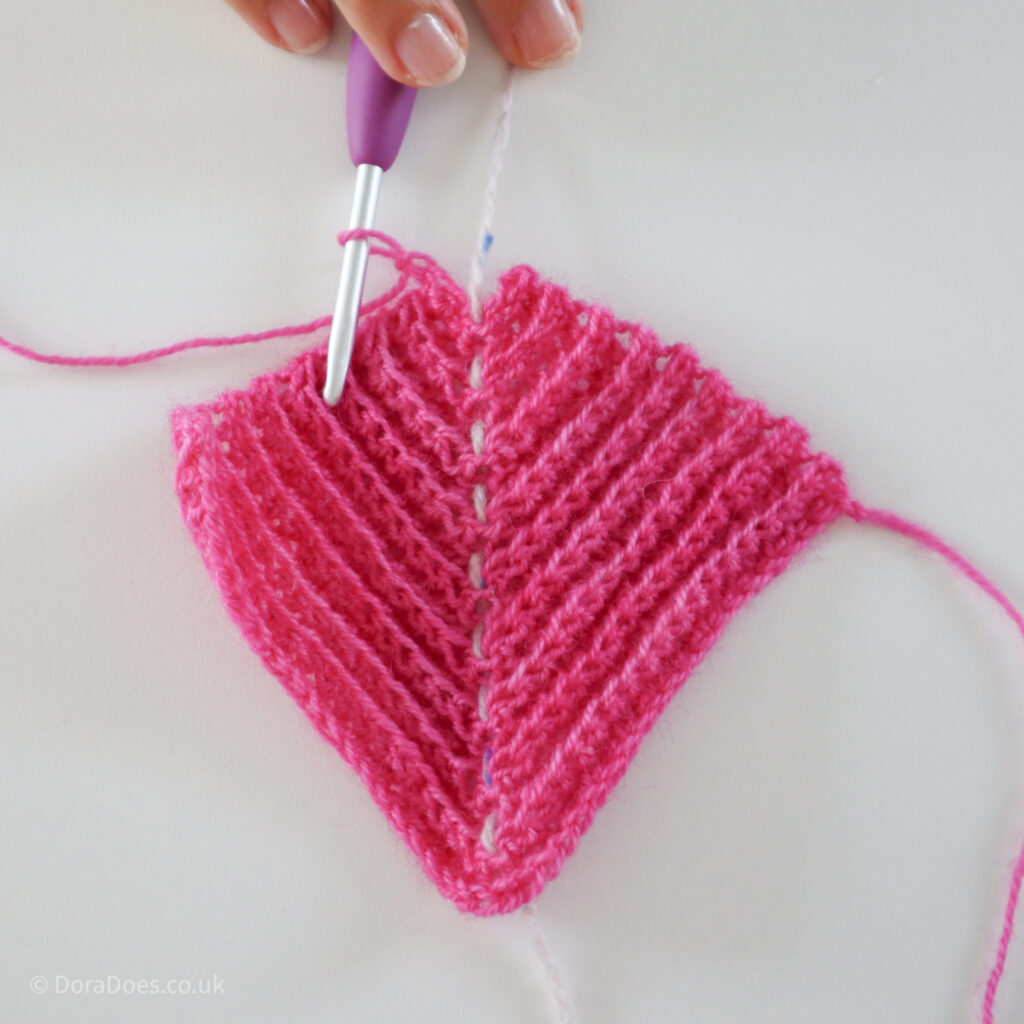 Crochet mitred square tutorial using pink yarn and a 4mm crochet hook with only 5 stitches remaining in the penultimate row: Step 15.