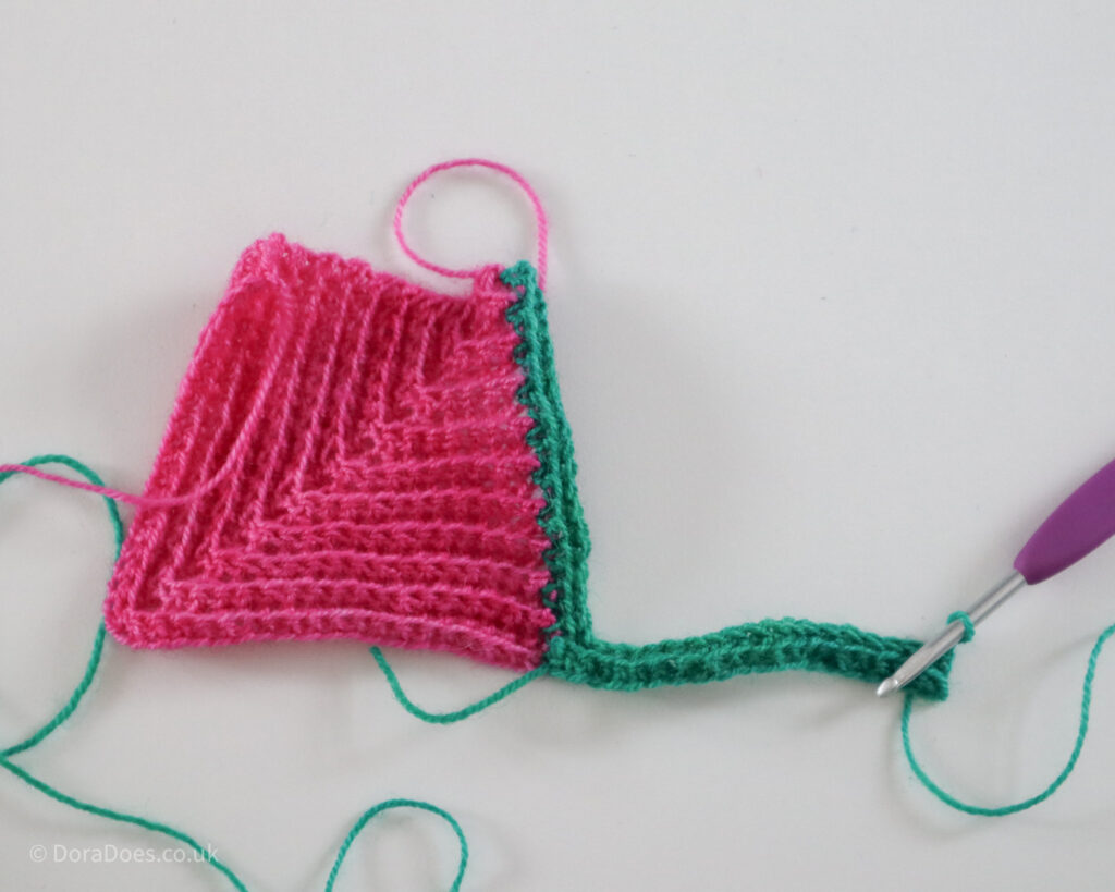 The second row of a second crochet mitred square has been worked into a first mitred square.