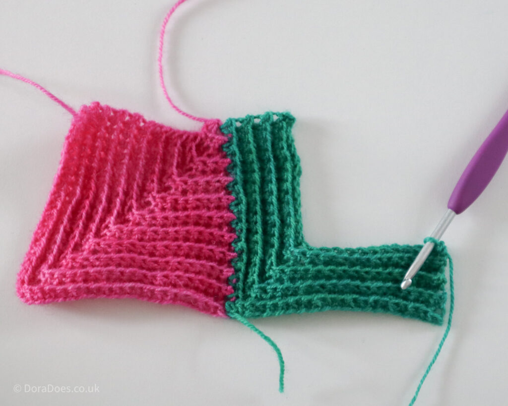 Half of a green mitred square had been crocheted into a complete pink mitred square as part of the joining tutorial.