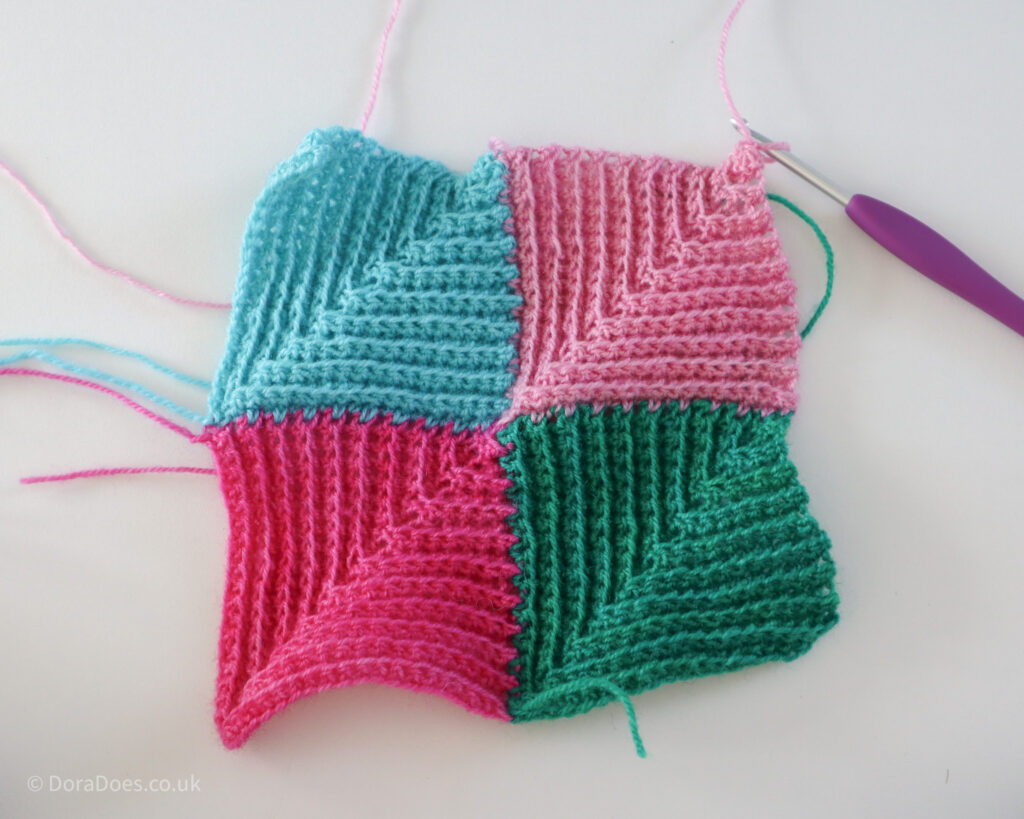 Four crochet mitred squares in different colour yarns have been made and joined together as they were created. The last step of a crochet mitred square joining tutorial.