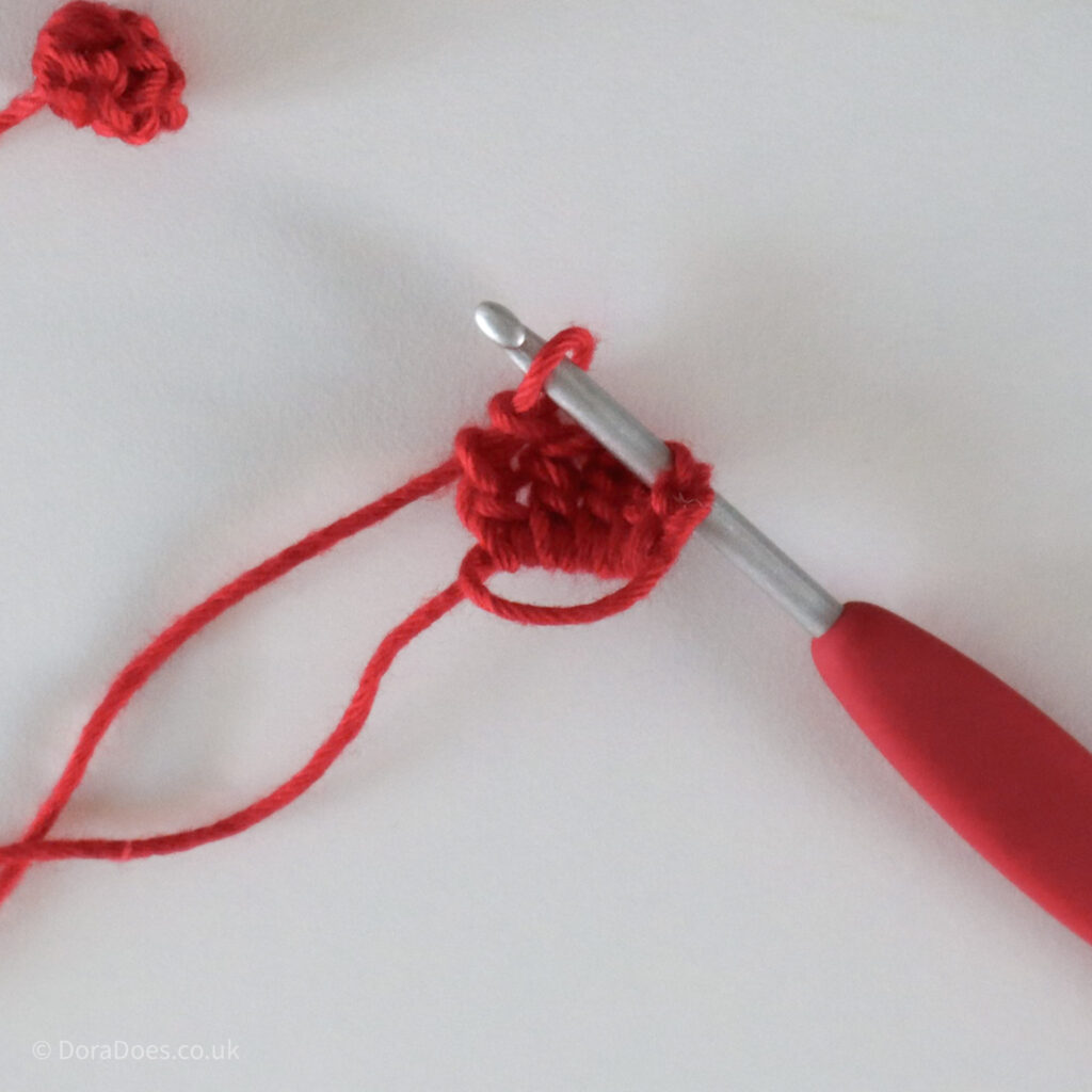 Crochet Holly Berry Tutorial step showing the popcorn stitch being made.