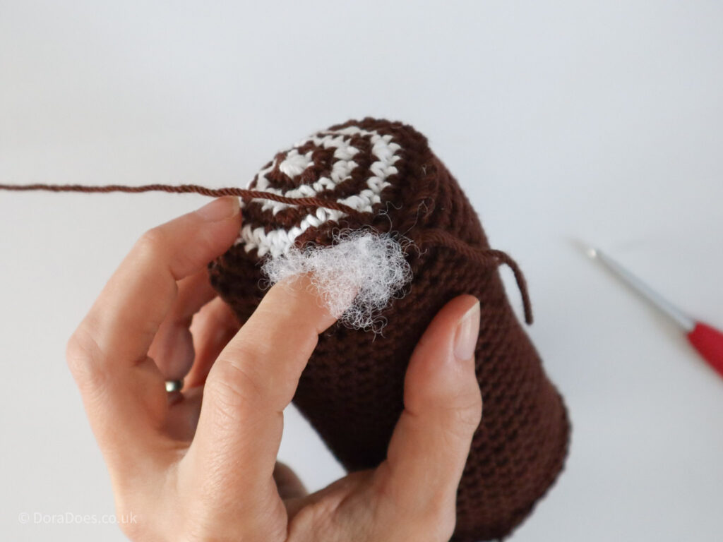 A close up of the last bit of stuffing being poked into the centre of a crochet Yule Log.