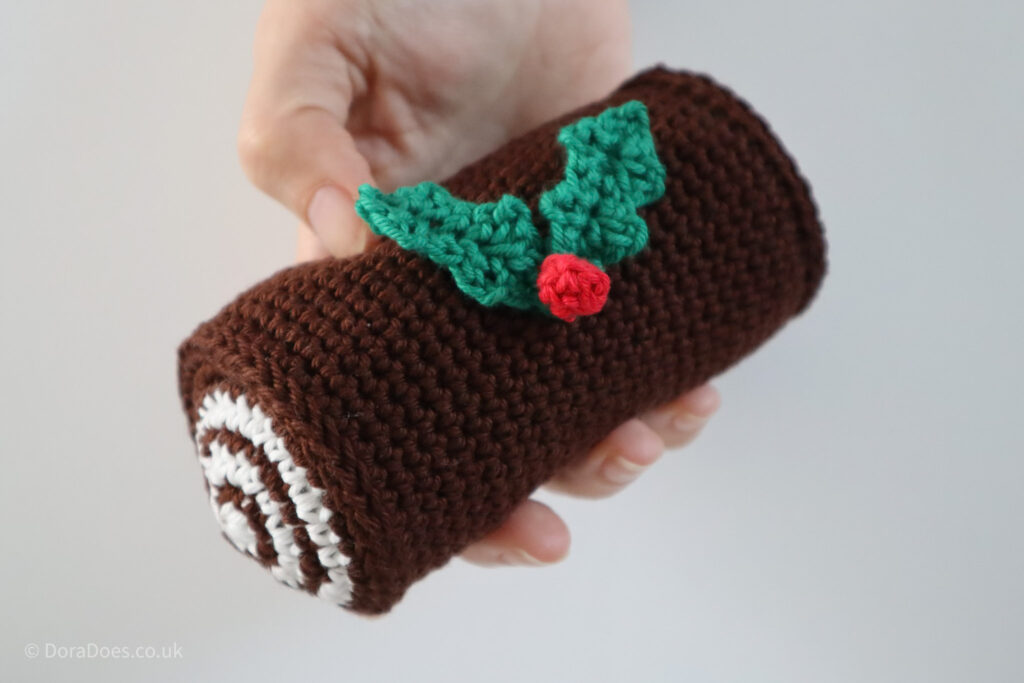 The constructed crochet Yule log after the ends have been sewn in and the holly attached.