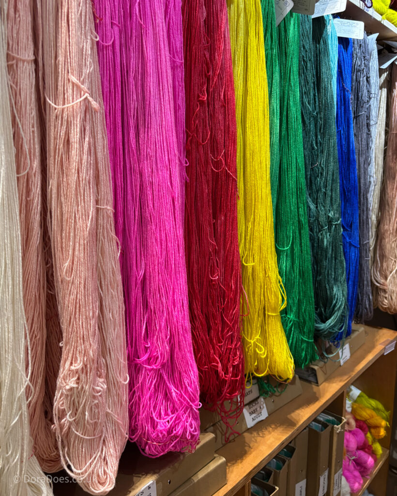 A rainbow of un-wound skeins of masham wool yarn, hand dyed in a range of bought, saturated colours.