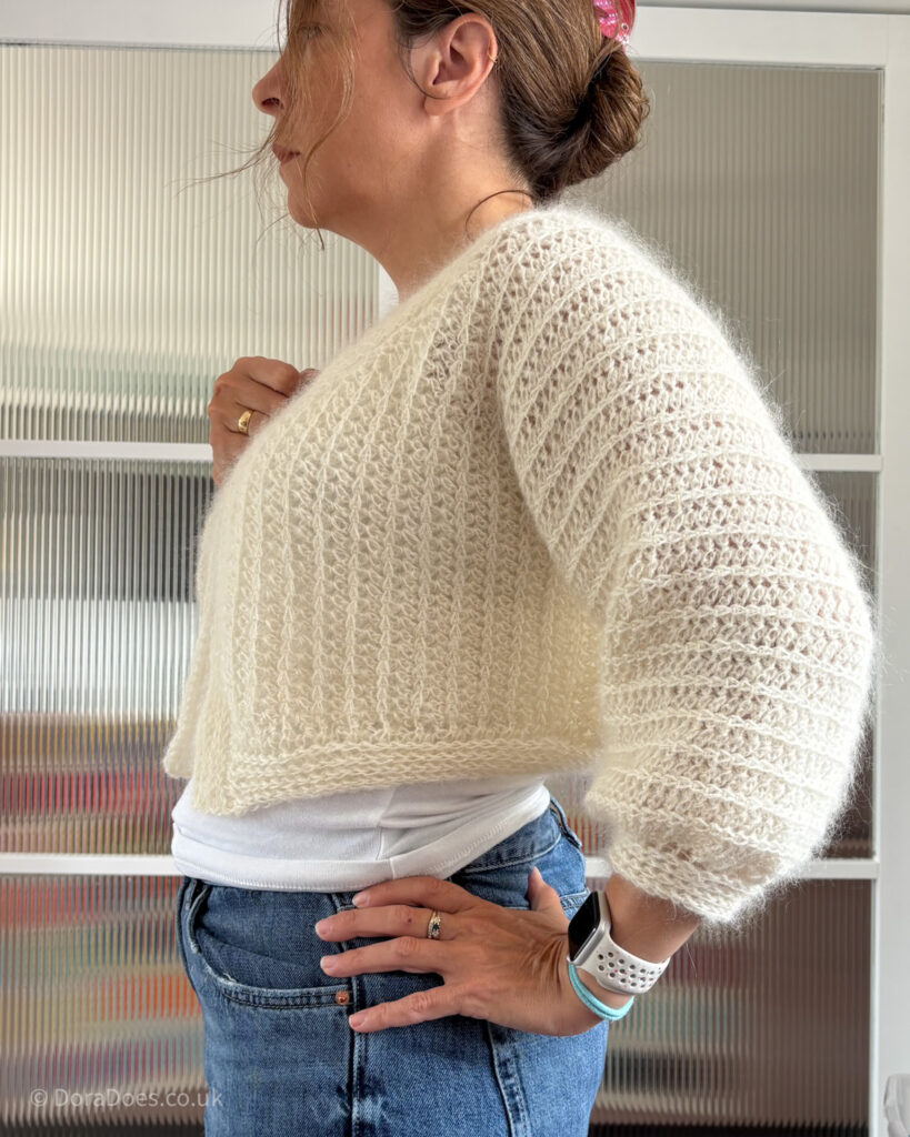 A side view of Dora wearing a cropped cream version of the fluff it cardigan made from a combination of kid silk mohair and alpaca yarn.