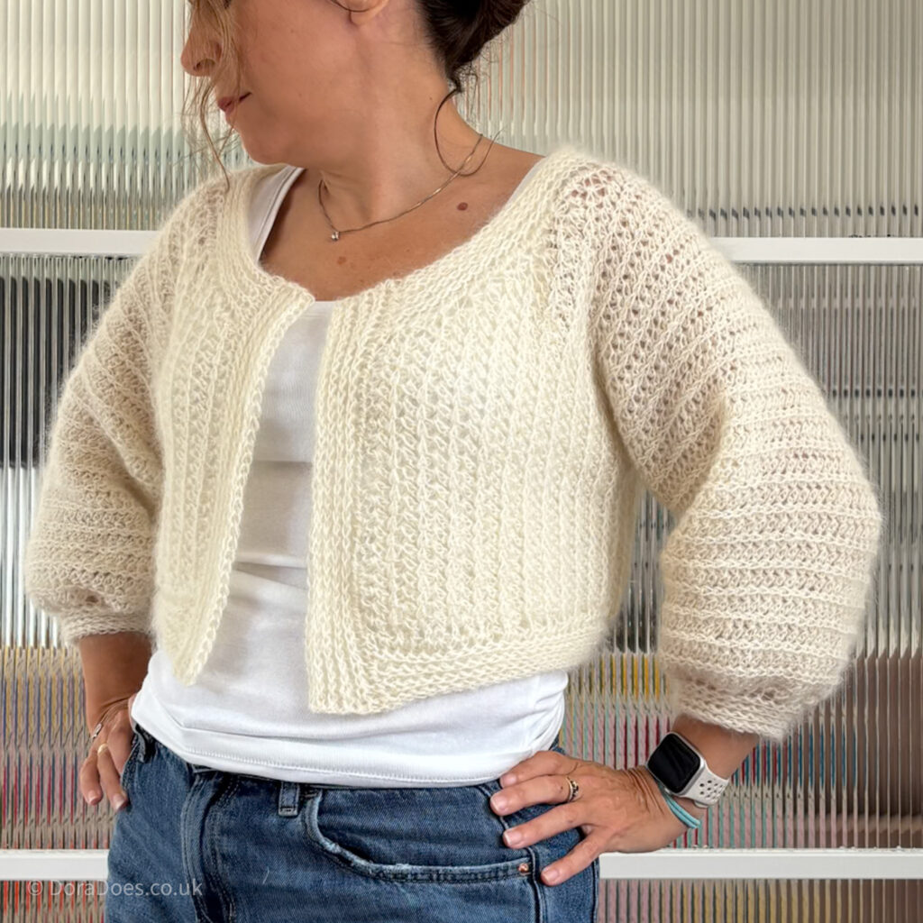 Dora is seen from the front wearing a cropped 3/4 length sleeves version of the ‘fluff it’ cardigan.