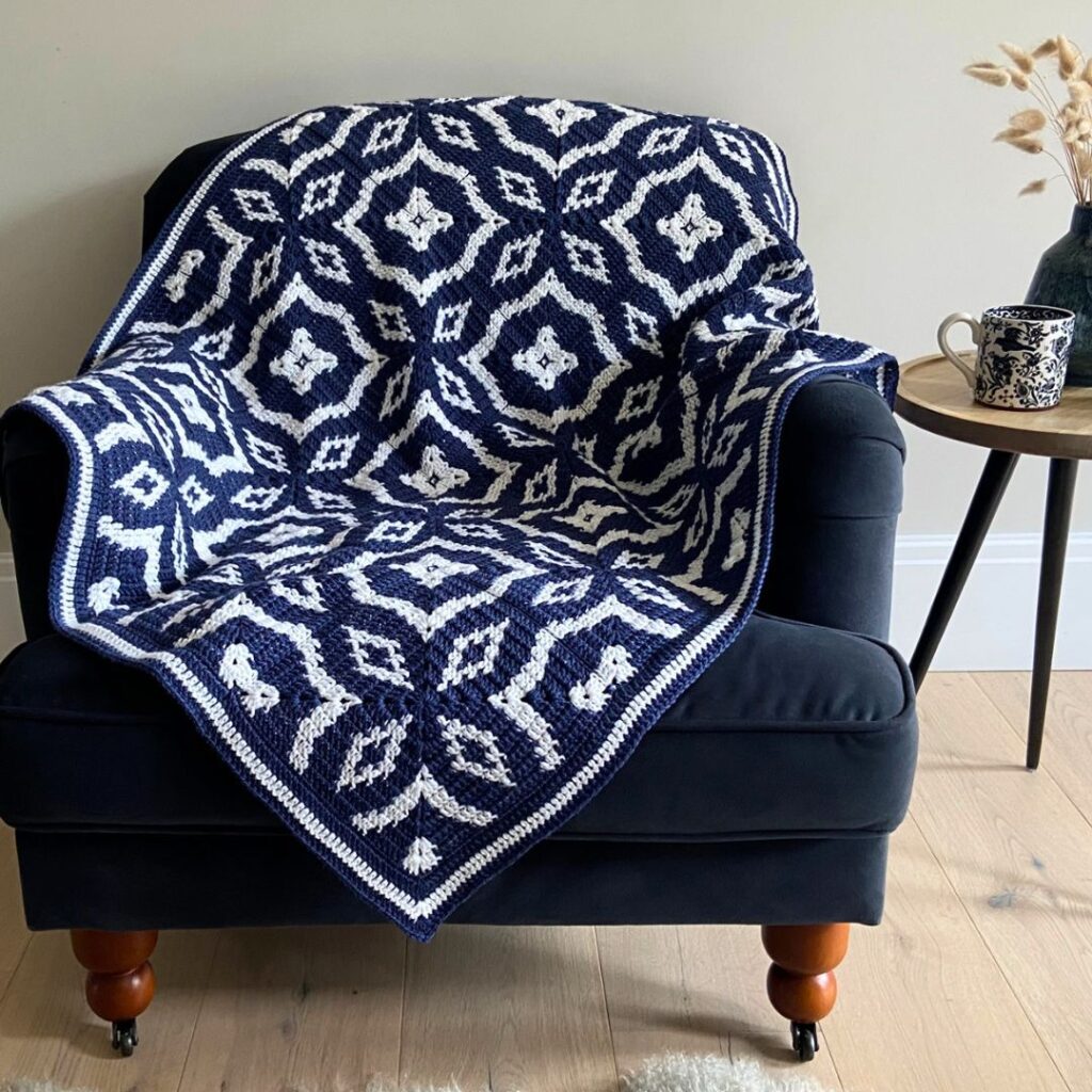 A navy and white crochet blanket with a tessellating diamond pattern.