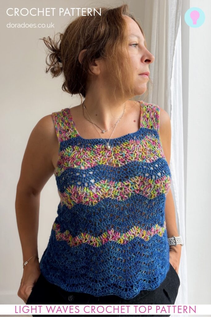 A woman wearing a striped chevron wave stitch crochet vest in two colours looks out a window. A text overlay reads crochet pattern, Doradoes.co.uk and Light Waves Crochet Top Pattern.