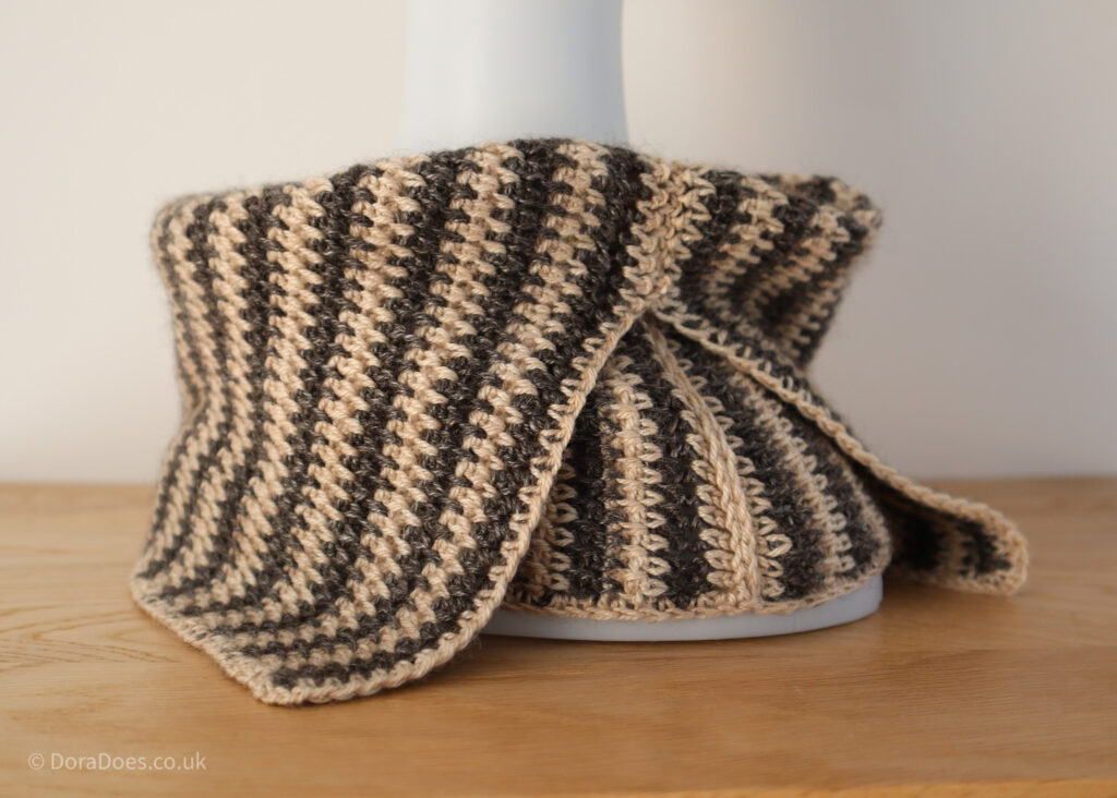 A landscape invade of a double layer crochet cowl. The join is only made 2/3 the way up the short side, allowing the top to fold over and split to create a type of collar for a more practical fit.
