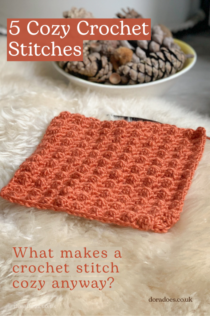 A textured crochet swatch in an autumnal orange yarn on a fluffy rug with a bowl of pine cones in the background. A text overlay reads '5 cozy crochet stitches, what makes a crochet stitch cozy anyway?'