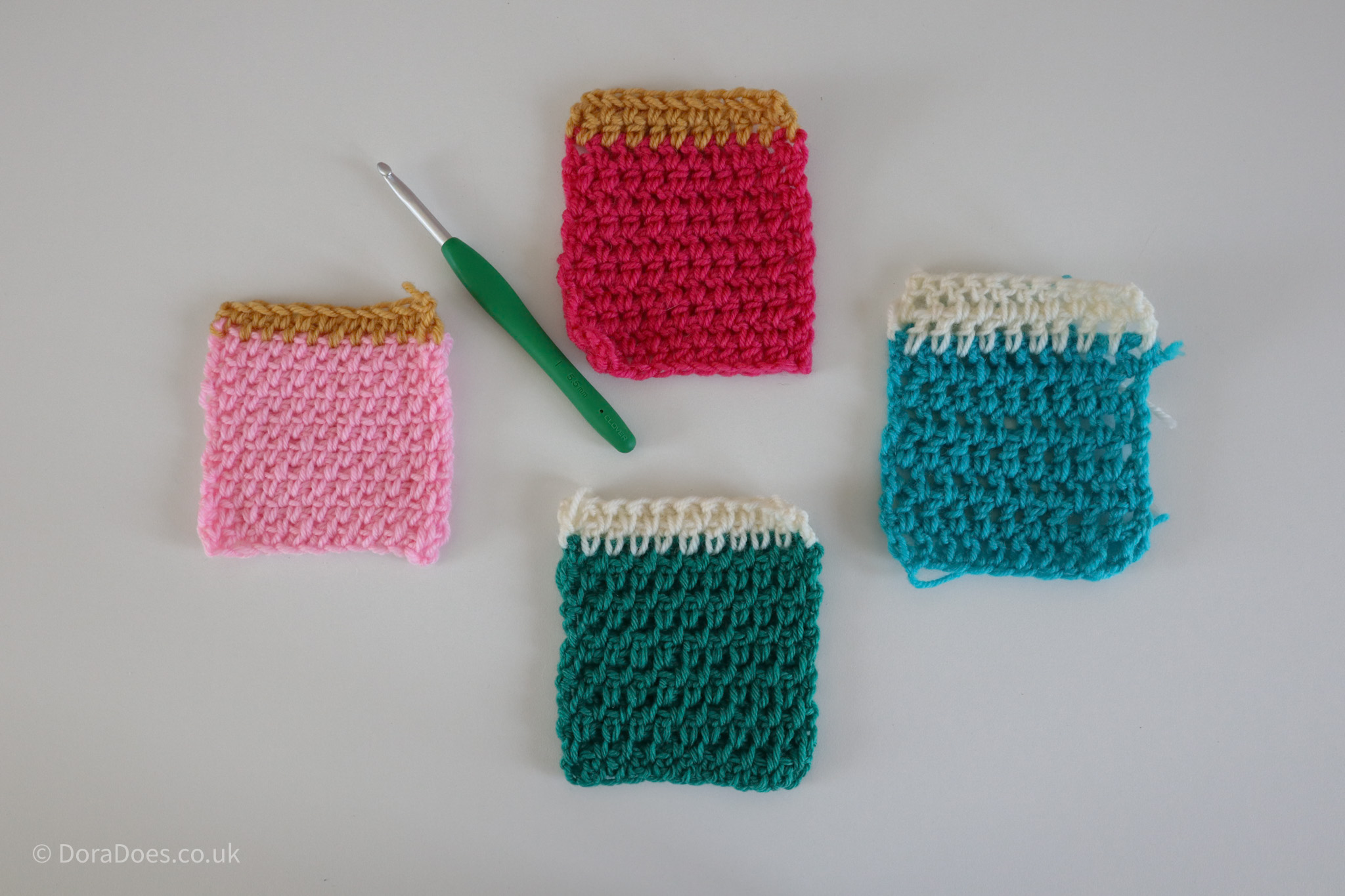 Four crochet swatches in two colours with a crochet hook lie on a flat surface. The crochet swatches are all made up of stitches crocheted between the posts. The swatches are made of single crochet, extended single crochet, half double crochet and double crochet worked between the posts.