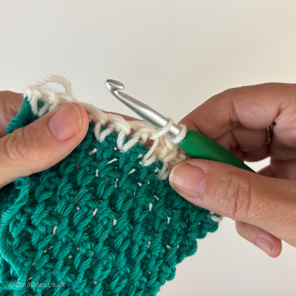 A close up of extended single crochet being made between the posts.