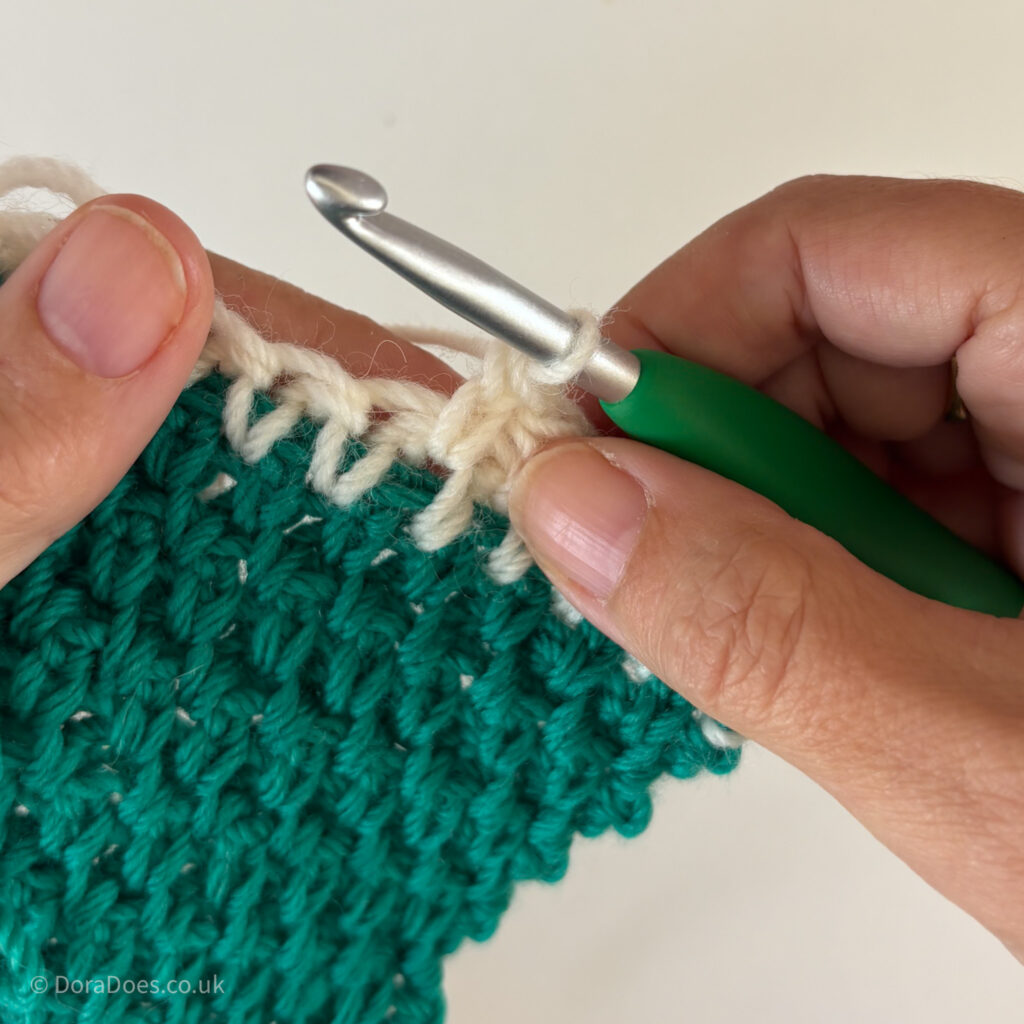 A close up of an extended single crochets between made in cream yarn between the posts.